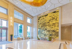 A spacious lobby with a high ceiling, large windows, and a mural on the wall. - Holiday Inn Foshan Nanhai Central by IHG (Foshan)