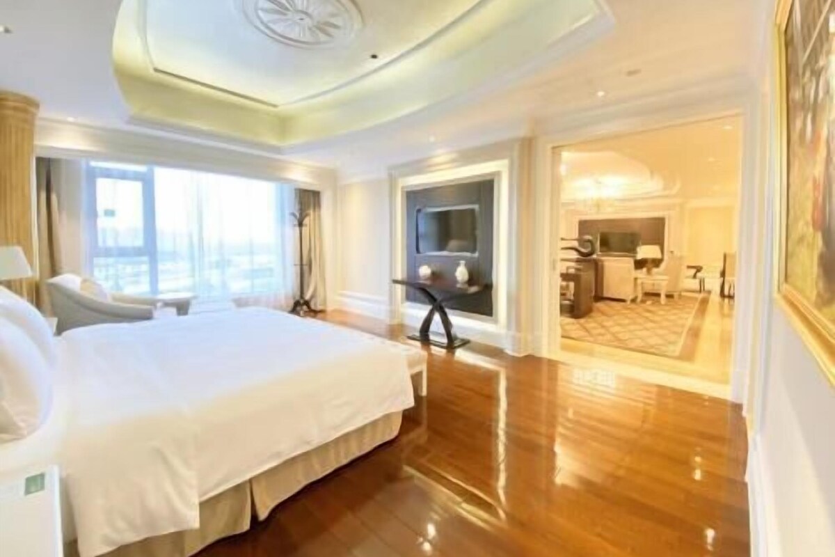 Une chambre d’hôtel spacieuse, dotée d’un grand lit, d’un coin salon et offrant une vue sur la ville.