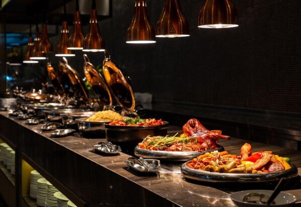 A buffet with various dishes and a long counter. - Holiday Inn Foshan Nanhai Central by IHG (Foshan)