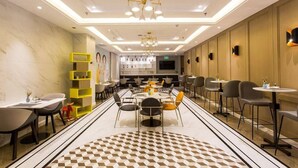 A modern hotel lobby with a central dining area, multiple seating options, and a decorative geometric floor pattern. - Magnotel Yingda Road, Baoji (Baoji)
