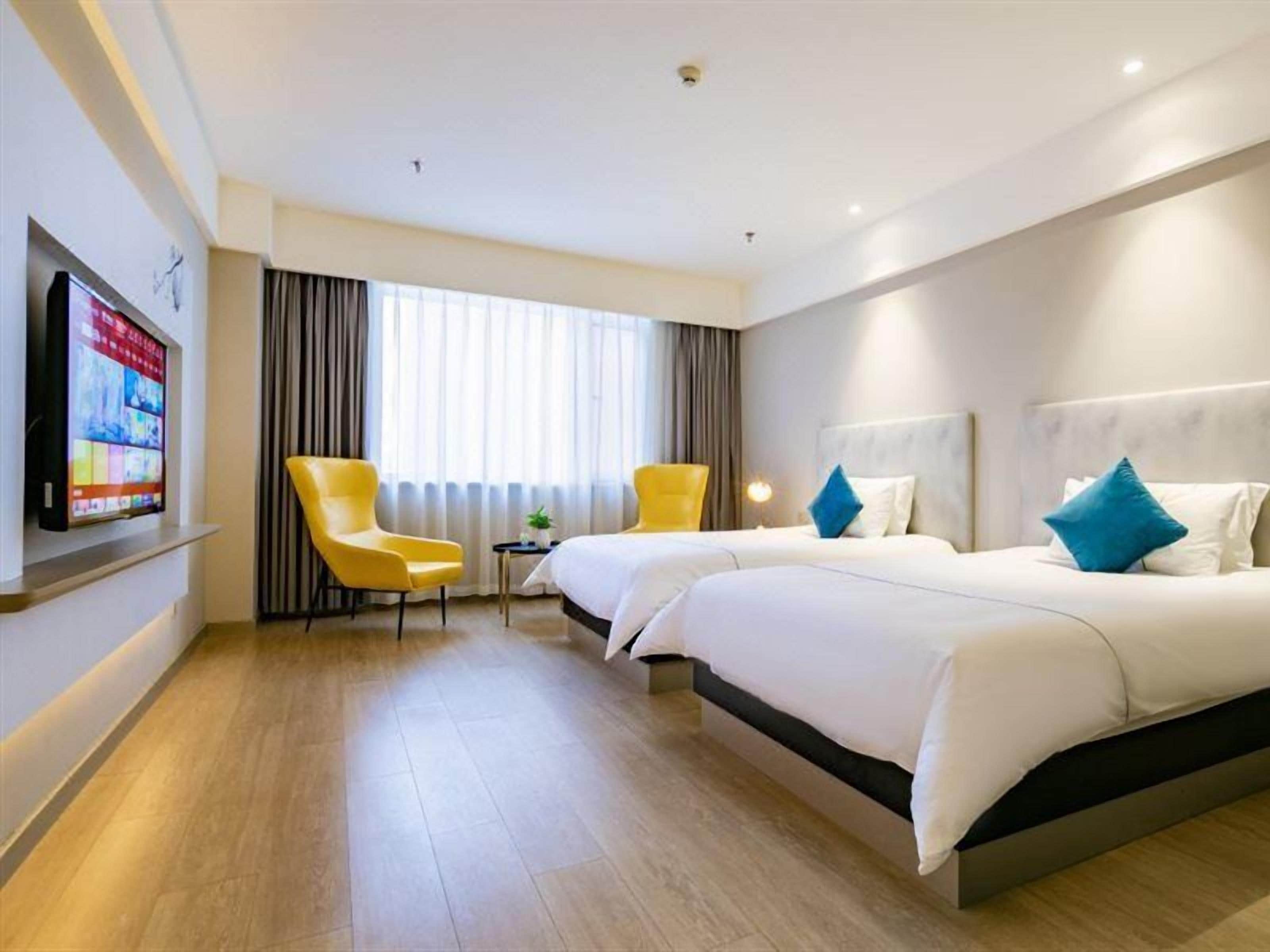 A hotel room with two beds, a flat-screen TV, a small table, and a chair.