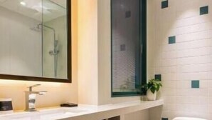 A modern bathroom with a large mirror, a white sink, a toilet, and a window. - Magnotel Yingda Road, Baoji (Baoji)