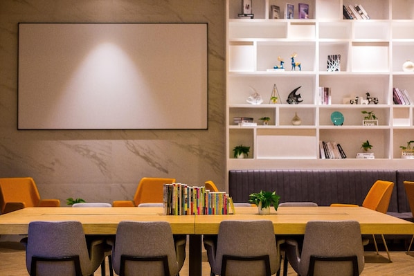 A conference room with a long table, multiple chairs, a bookshelf, and a large blank screen on the wall. - Magnotel Yingda Road, Baoji (Baoji)