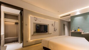 A modern hotel room with a bed, a TV mounted on the wall, a built-in closet, and a small shelf with toiletries. - Magnotel Yingda Road, Baoji (Baoji)
