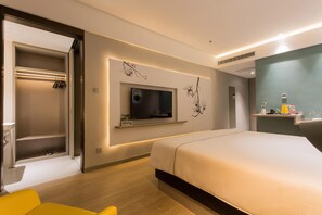 A modern hotel room with a bed, a TV mounted on the wall, a built-in closet, and a small shelf with toiletries. - Magnotel (Baoji)