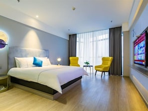 A hotel room with a bed, two chairs, a television, and a window with curtains. - Magnotel Yingda Road, Baoji (Baoji)