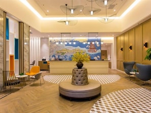 A hotel lobby with a reception desk, seating area, and a decorative centerpiece. - Magnotel Yingda Road, Baoji (Baoji)