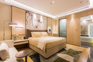 Una habitación de hotel moderna con una cama grande, mesitas de noche, un escritorio y un área de estar.