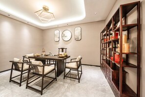 A dining area with a dark wooden table and chairs, a bookshelf with various items, and wall-mounted decor. - Holiday Inn Express Jinjiang Anhai (Quanzhou)