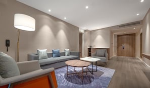 A modern hotel room with a sofa, armchair, round coffee table, and a lamp. - Holiday Inn Express Jinjiang Anhai (Quanzhou)