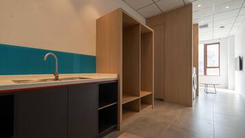 A modern kitchen with a sink, cabinets, and a countertop. There is a wooden cabinet and a window in the background.