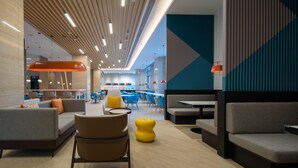 Um espaço interior moderno com áreas de estar, mesas e um pilar central com design único.