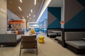 Un espacio interior moderno con zonas de estar, mesas y una columna central de diseño único.