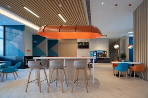 Un interior moderno con una zona de bar, asientos y una lámpara colgante grande color naranja.