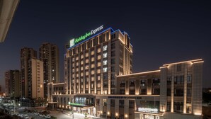 Um hotel com vários andares, com um letreiro chamativo 'Holiday Inn Express', um restaurante no térreo e uma área de estacionamento.
