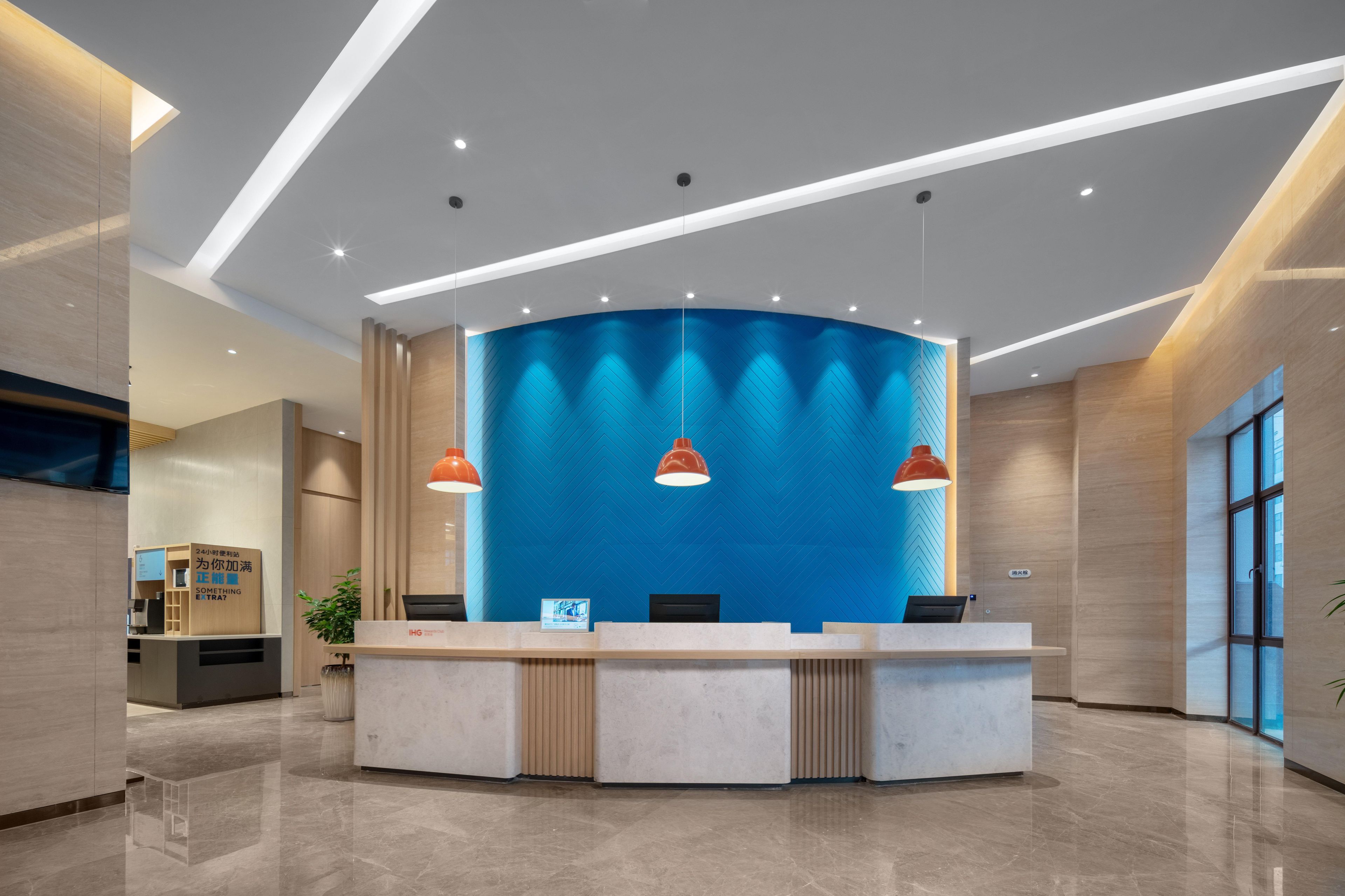 Un mostrador de recepción moderno con una pared azul de acento, iluminación colgante y un suelo limpio y pulido.