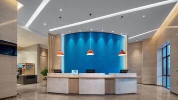 Un mostrador de recepción moderno con una pared azul de acento, iluminación colgante y un suelo limpio y pulido.