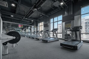 Un gimnasio con cintas de correr, máquinas de pesas y amplias ventanas.