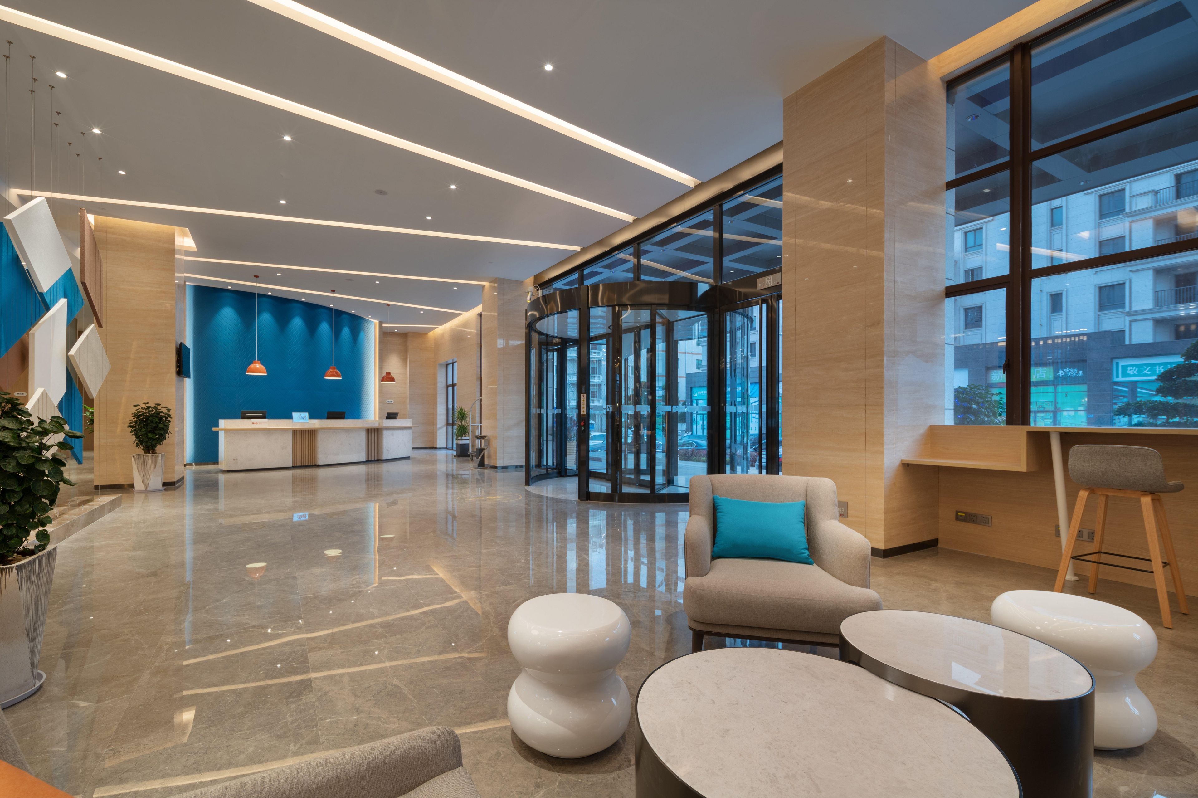 Una hall moderna con reception, zona salotto e ampie finestre.