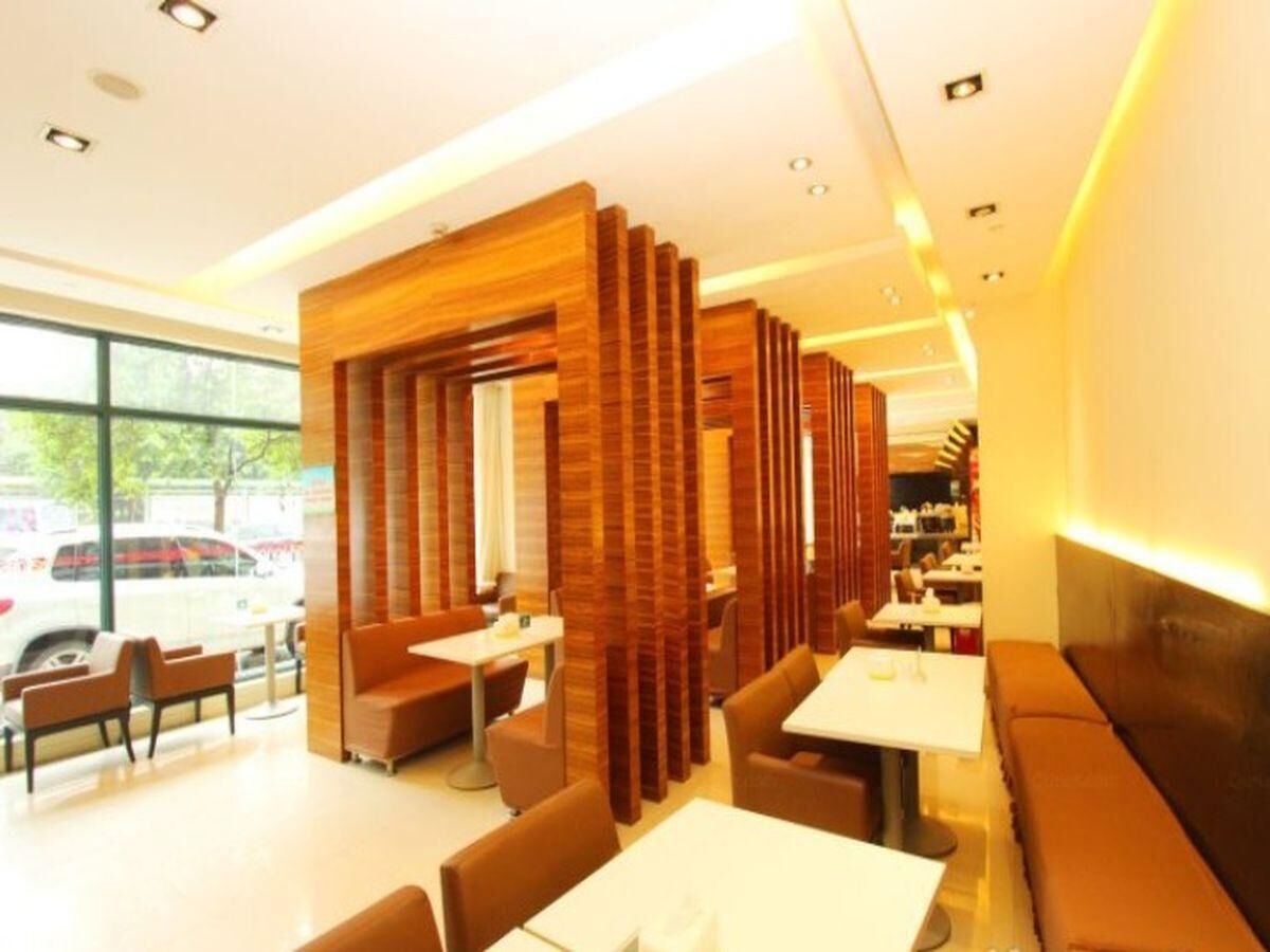 Interior moderno de restaurante com divisórias de madeira, disposição de assentos e vista para o exterior.