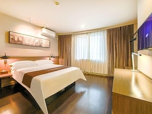 A hotel room with a large bed, a flat-screen TV, a desk, and a window with curtains. - Jinjiang Inn Select (Wuhan)