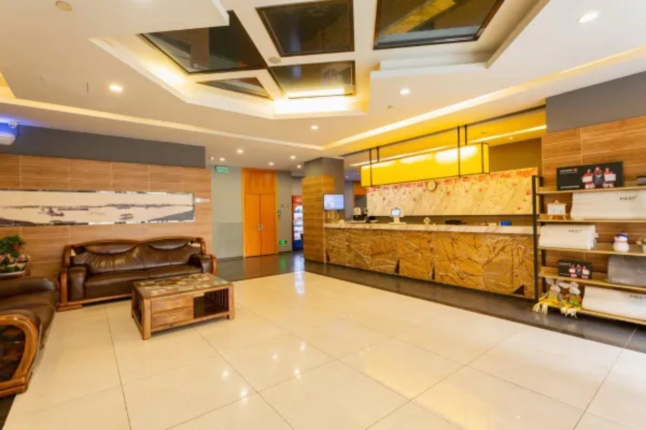 A hotel lobby with a reception desk, seating area, and a large window.