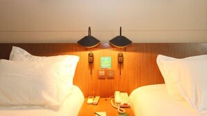 A hotel room with two beds, a wooden headboard, two wall-mounted lamps, a telephone, and a framed picture above the beds. - Jinjiang Inn Select Hotel (Wuhan)