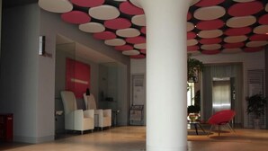 A spacious lobby with a modern design, featuring a large white column, seating areas, and a visible elevator. - Jinjiang Inn Select Hotel (Wuhan)