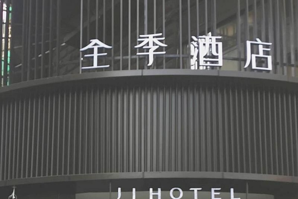 A hotel entrance with a modern design, featuring a large sign with Chinese characters and the word 'HOTEL' in English.