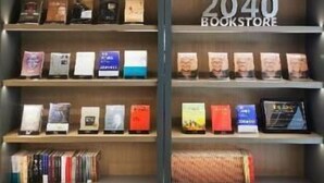 Una llibreria amb prestatges plens de llibres i un cartell que diu '2040 BOOKSTORE'.