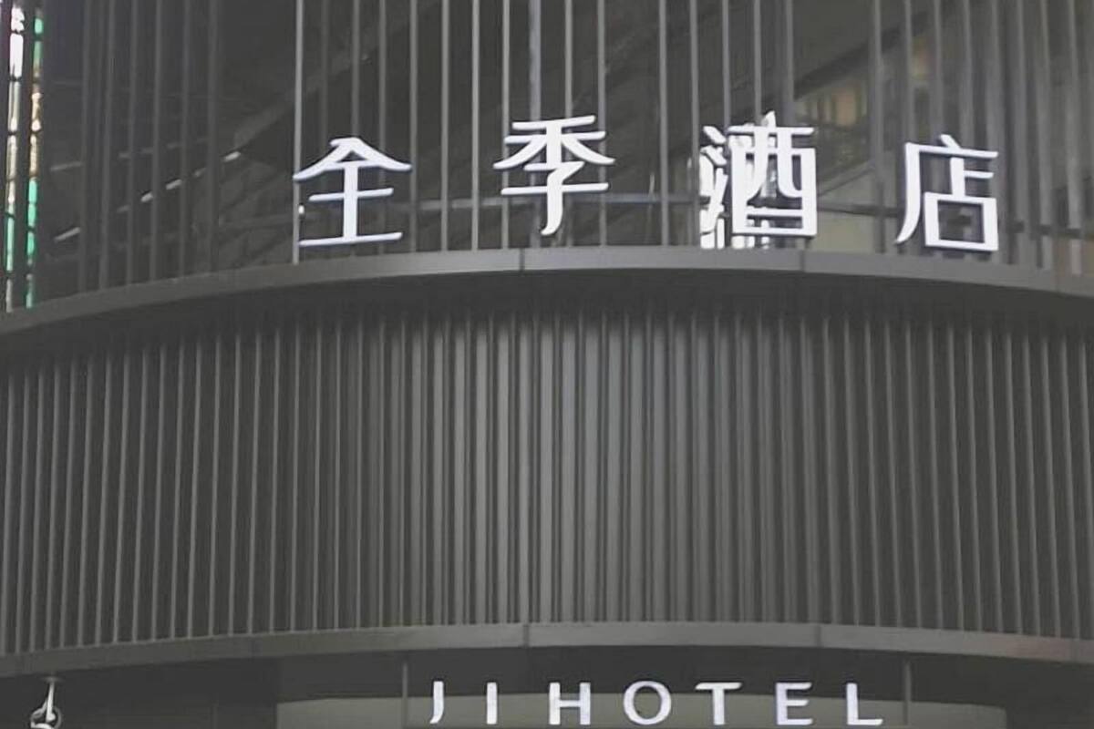 A hotel entrance with a modern design, featuring a large sign with Chinese characters and the word 'HOTEL' in English.