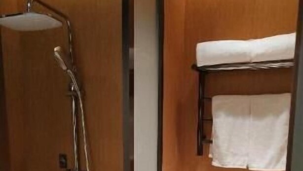 Ein kleines, kompaktes Badezimmer mit Dusche, Handtuchhalter und Toilette.