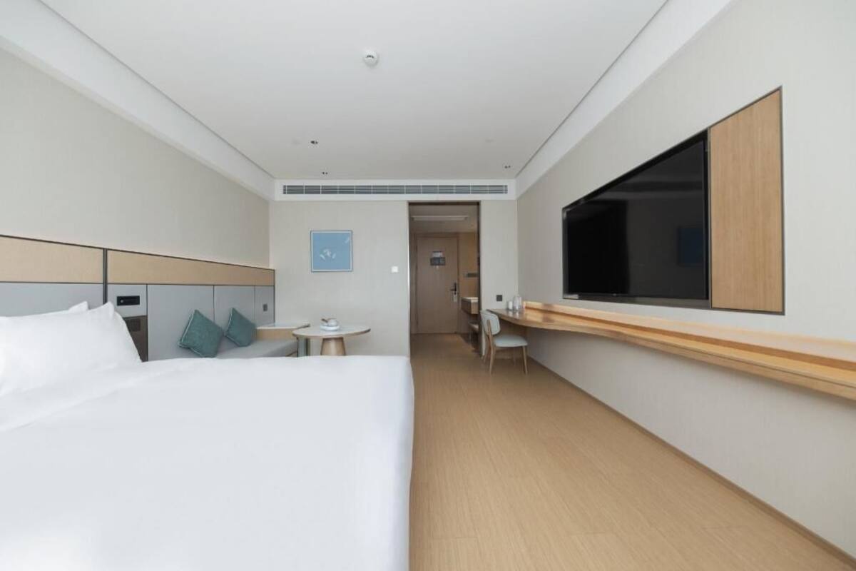 Une chambre d’hôtel avec un lit, une télévision, un bureau et une chaise.
