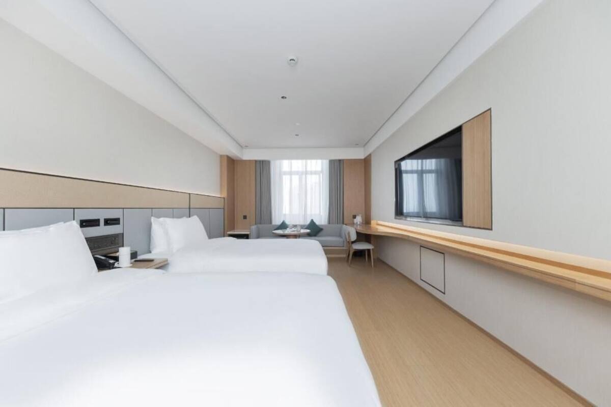Une chambre d’hôtel avec trois lits, une télévision, un bureau et une fenêtre.