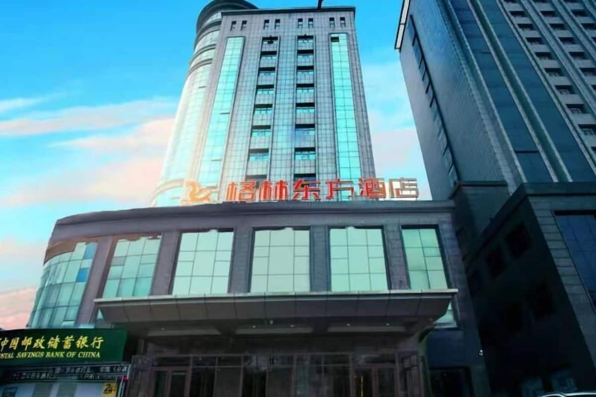 A hotel with a modern glass facade, a prominent entrance, and a sign for the China Postal Savings Bank of China.