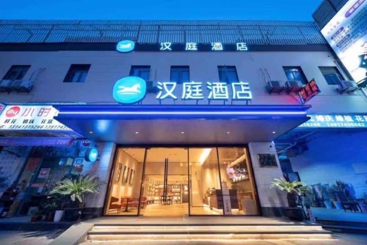 A hotel entrance with a sign reading '汉庭酒店' and a blue illuminated sign above.