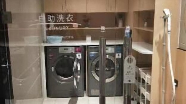 Un cuarto de lavandería con dos lavadoras, un tendedero y un aspirador.