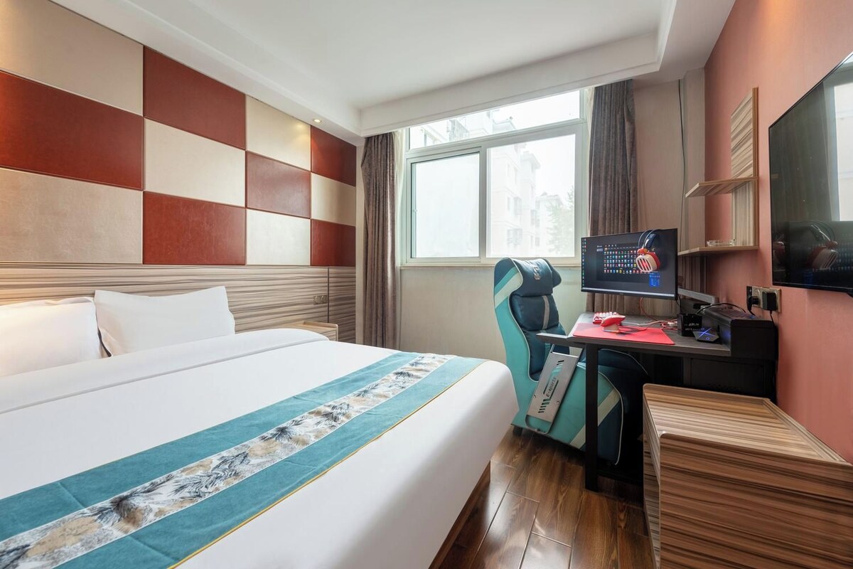A hotel room with a large bed, a desk with a computer, and a TV.