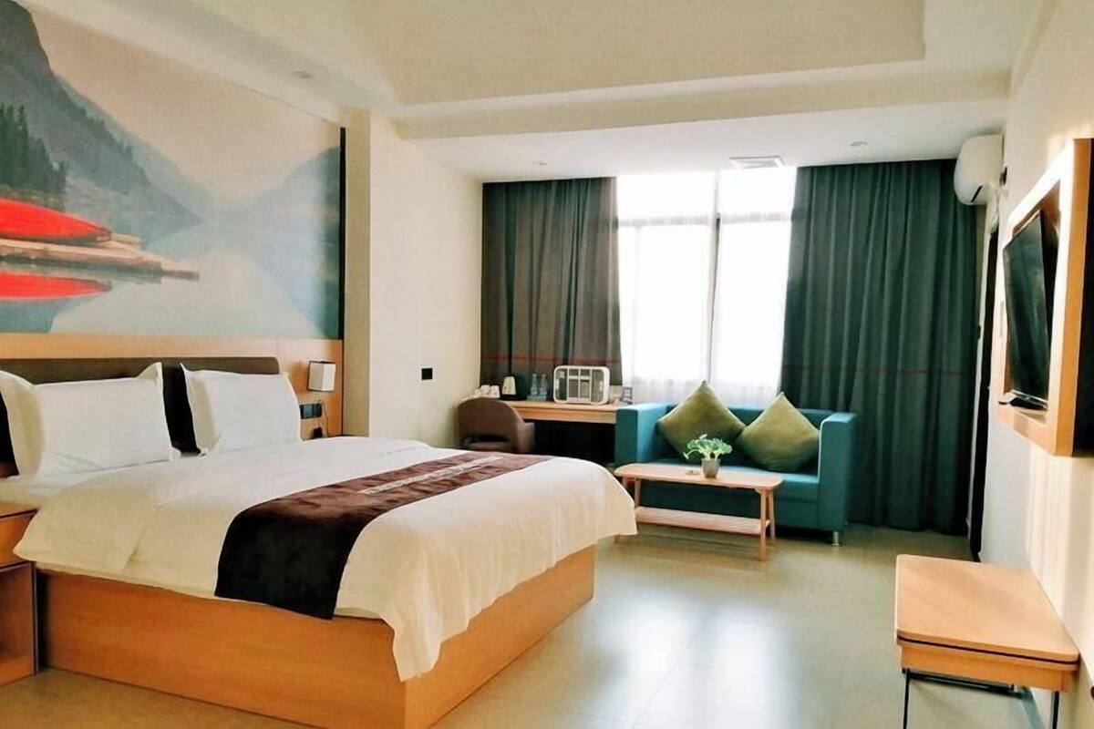 Et hotelværelse med en stor seng, et skrivebord, en sofa og et fjernsyn.