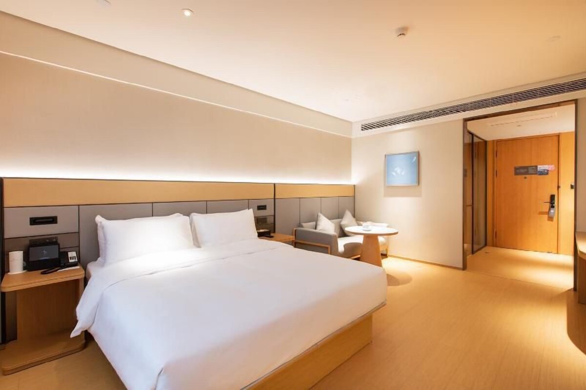 Una habitación de hotel moderna con una cama grande, mesitas de noche, un escritorio y una zona de estar.