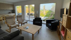 Un salon moderne comprenant un canapé, des fauteuils, une table basse et un meuble pour la télévision.