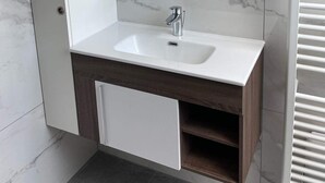 Une salle de bain avec un lavabo blanc, un miroir et un porte-serviettes.