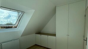 Une chambre avec un puits de lumière, un lit, une armoire et un radiateur.