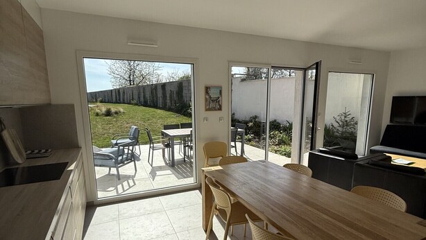 Une cuisine avec un coin repas, de grandes fenêtres et une vue sur le jardin arrière.
