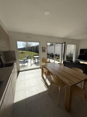 A kitchen with a dining area, large windows, and a view of the backyard. - Baie de Somme: 125-square-meter vacation rental with a 700-square-meter fenced-in lot (Boismont)