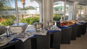 Montaje de bufé con varios recipientes y utensilios para alimentos sobre una mesa, con vista a la vegetación exterior.