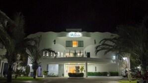 Un hotel con fachada curva, entrada central y palmeras al frente.