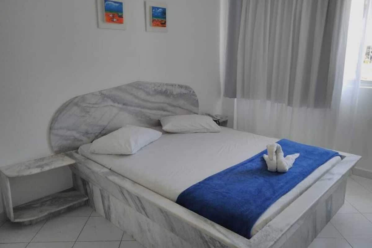 Ein Bett mit einem Marmorkopfstück, einem blauen Handtuch und einem kleinen Nachttisch.