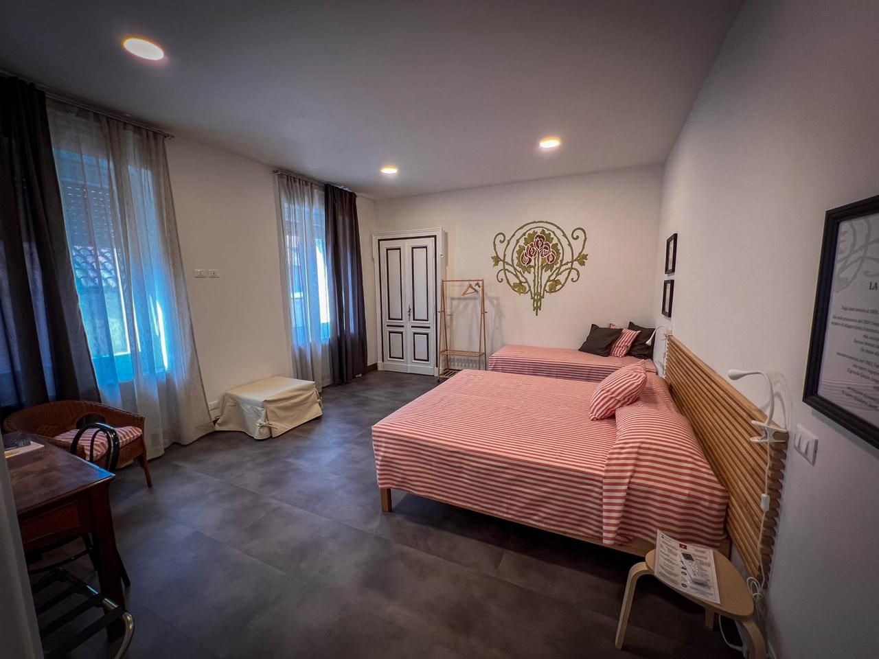 Ein Schlafzimmer mit Bett, Nachttisch, Stuhl und einem Fenster mit Vorhängen.