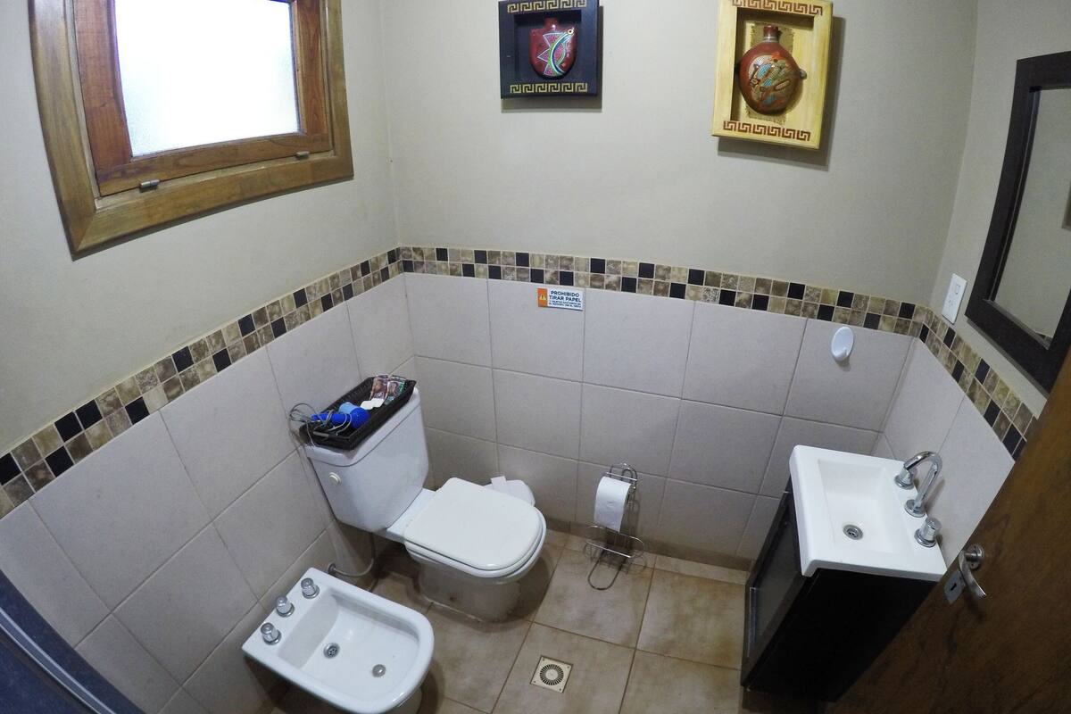 Ein Badezimmer mit Toilette, Bidet, Waschbecken und dekorativen Fliesen.